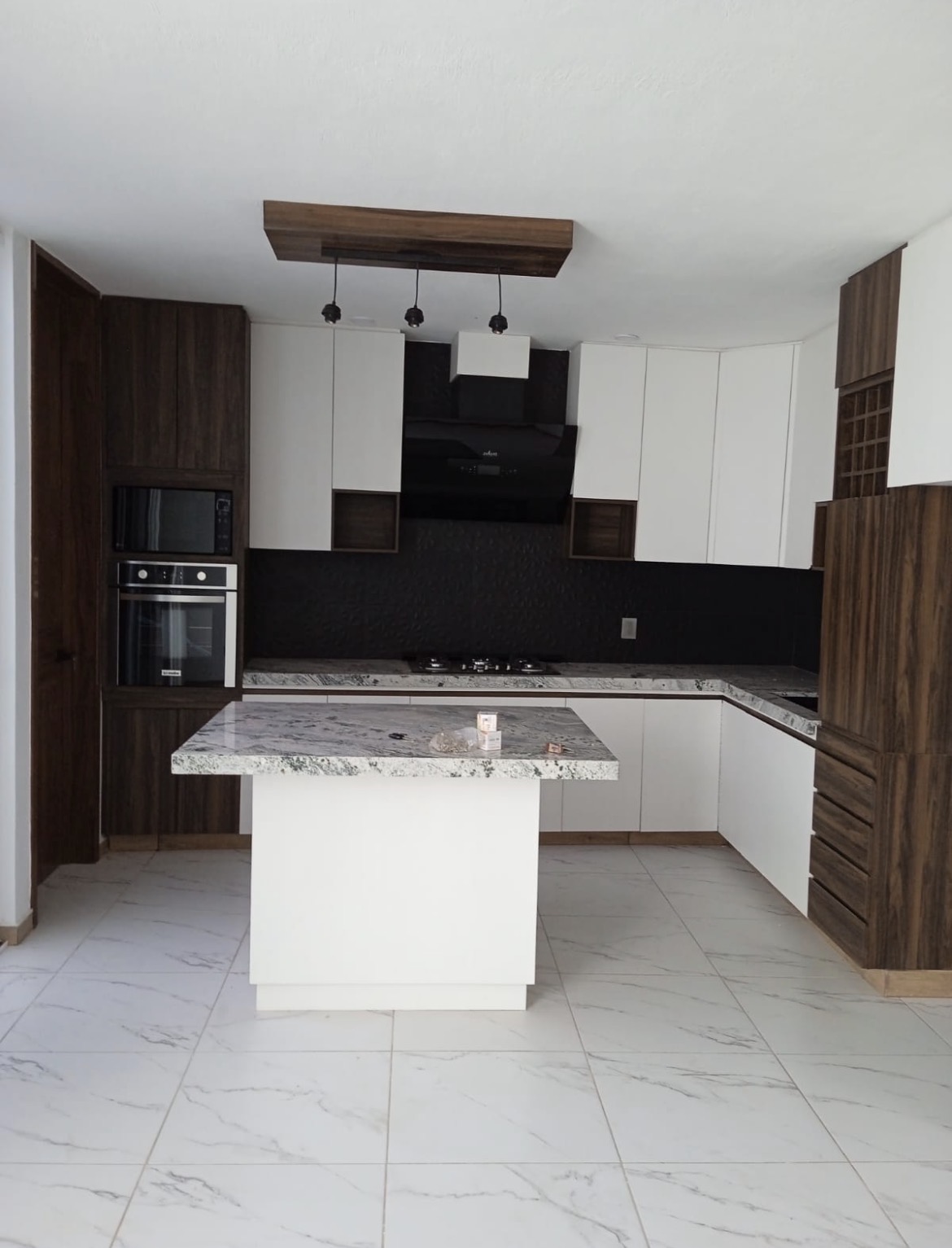 White kitchen with walnut columns and marble island